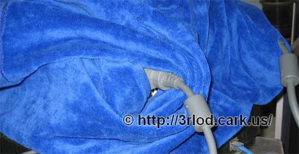Close up of the Xbox 360 wrapped in the towel. Video cable still plugged in.